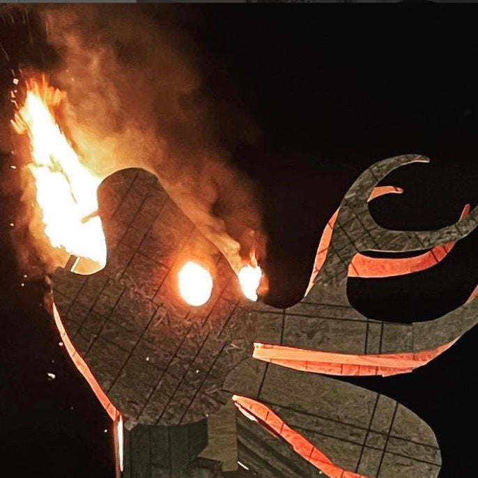 Fun image of large animal-shaped wood sculpture with fire out of mouth