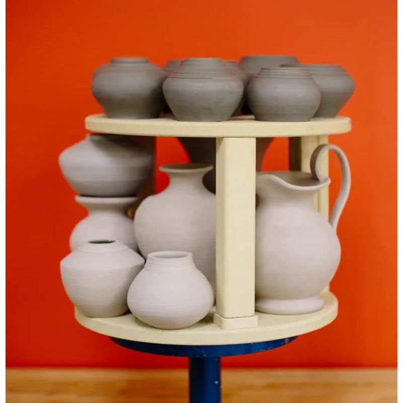 Multiple unglazed ceramic pieces loaded onto two layers of shelves.