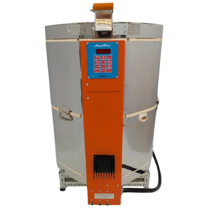Straight-on view of closed, round-shaped AF Mega-coil 2413 ceramics and pottery kiln from Jen-Ken with 3" chamber brick, sitting on a small metal stand and showing the electrical box with Orton AutoFire 4000 12-button controller.