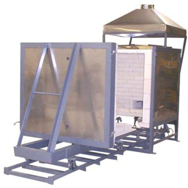 Angled front view of opened Olympic Kilns large capacity downdraft gas kiln - DD20 model - with sliding floor and front door opened and moved down a 6-foot car track. Partial view of interior firing chamber. Also shown is attached steel venting hood.