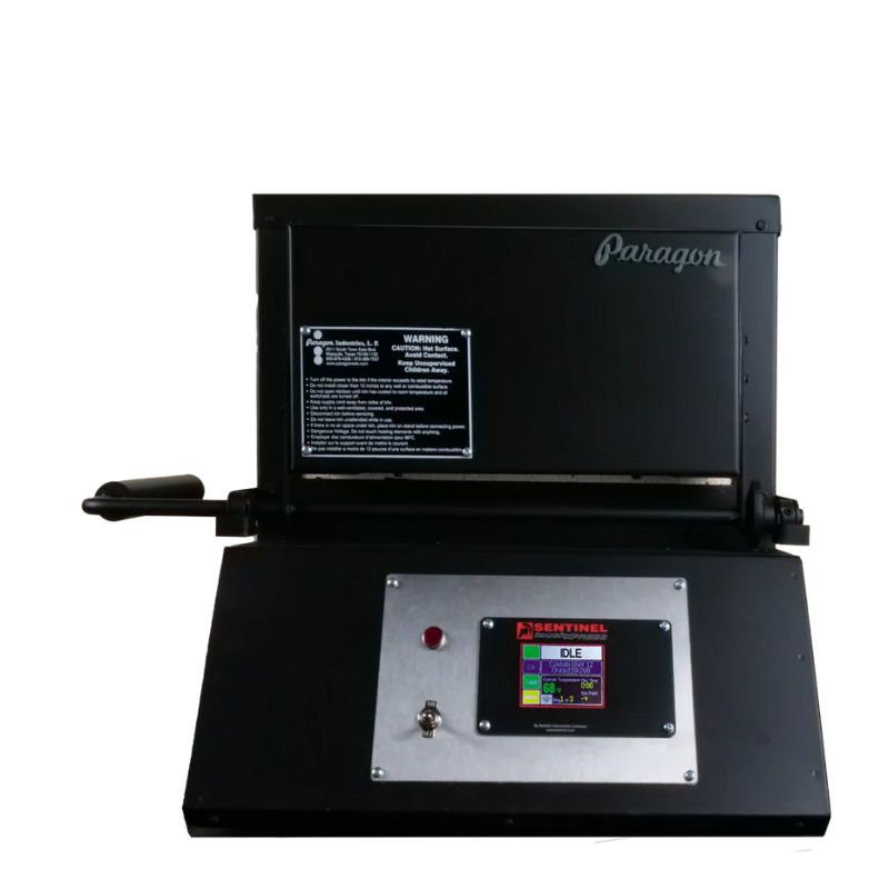 Straight-on view of closed KM9 Double Barrel Knife Making kiln from Paragon Kilns, in black color, with door handle on left and Sentinel TouchXpress controller beneath door.
