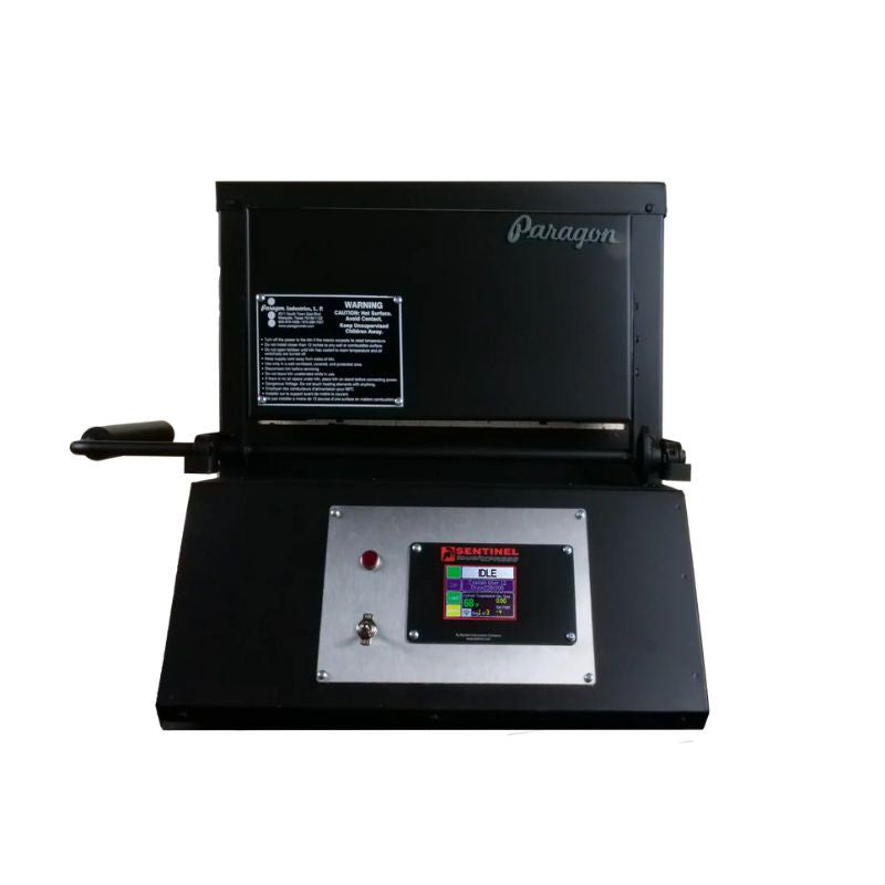 Straight-on view of closed KM24 Double Barrel Knife Making kiln from Paragon Kilns, in black color, with door handle on left and Sentinel TouchXpress controller beneath door.